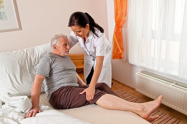 A nurse helping an old man get out of bed.