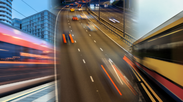 A train, cars and a bus, blurred by their motion